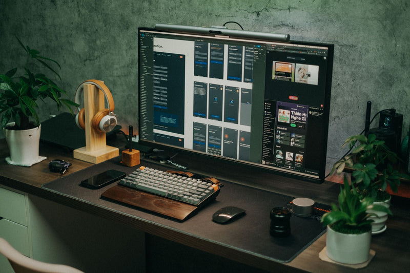 Wooden headphone stand with headphones on a commercial desk setup